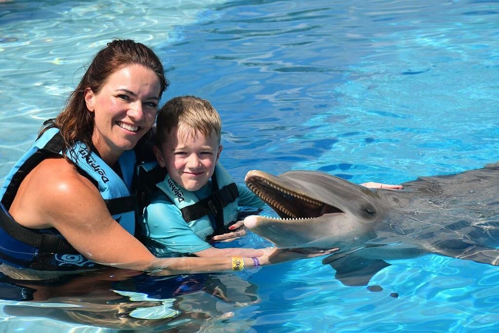 mom and son enjoying a swim with dolphins